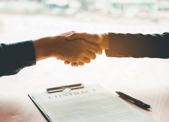 Business people negotiating a contract handshake between two colleagues